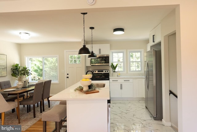 kitchen with a kitchen island, a breakfast bar area, hanging light fixtures, white cabinets, and appliances with stainless steel finishes