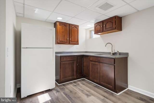 kitchen featuring sink, white fridge, a paneled ceiling, and light hardwood / wood-style floors