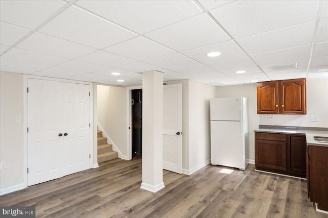 kitchen with hardwood / wood-style floors, a drop ceiling, and white fridge