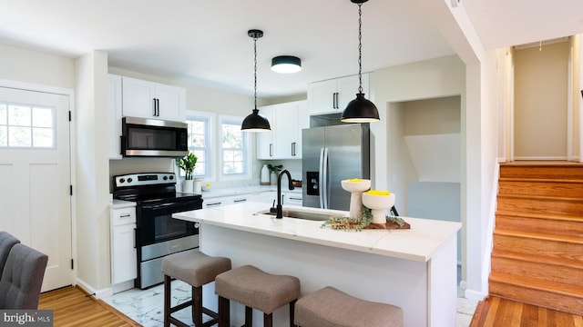 kitchen with sink, appliances with stainless steel finishes, a healthy amount of sunlight, and an island with sink