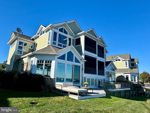 back of property with a sunroom and a lawn