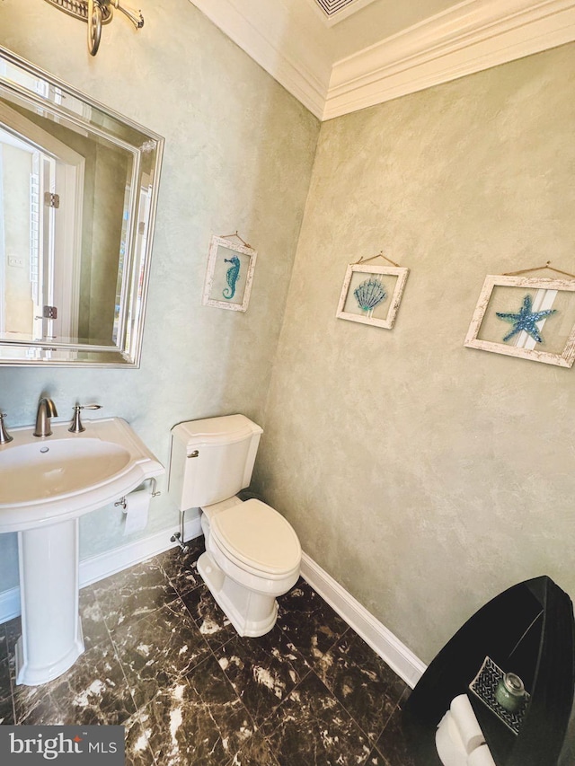 bathroom with toilet, ornamental molding, and sink