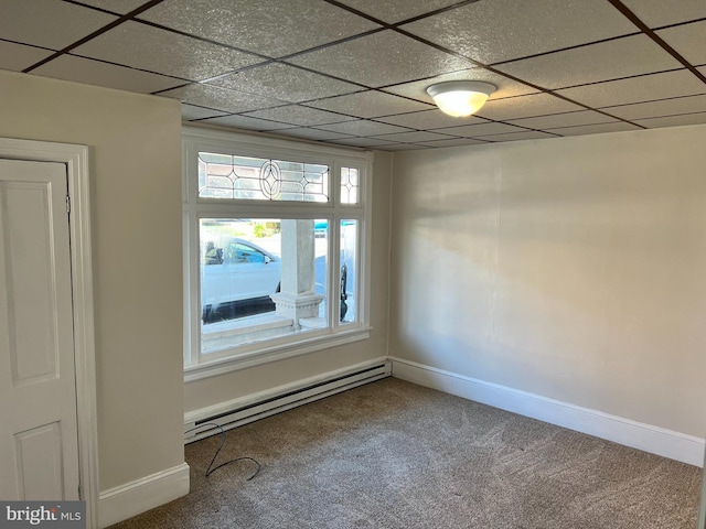 carpeted spare room featuring baseboard heating and a drop ceiling