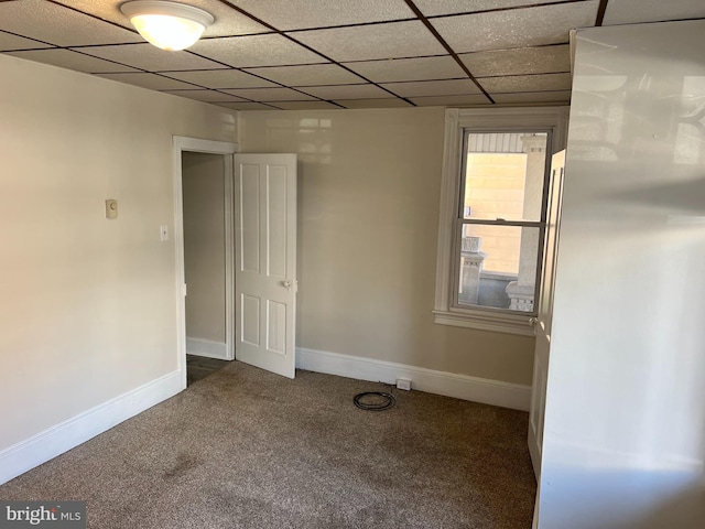 carpeted empty room featuring a drop ceiling