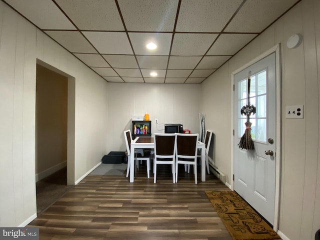 dining space featuring a baseboard radiator, dark hardwood / wood-style flooring, and a drop ceiling