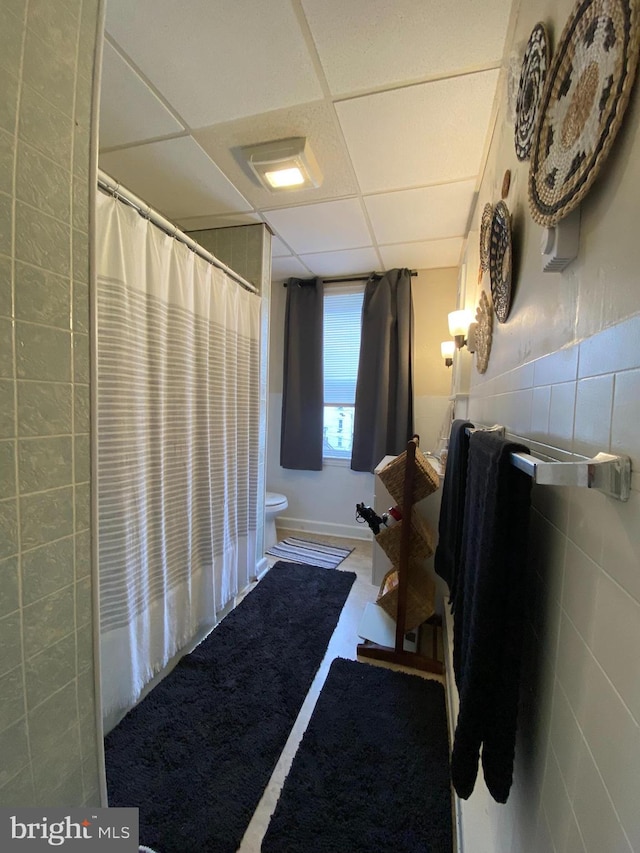 bathroom with toilet, a shower with curtain, and a drop ceiling