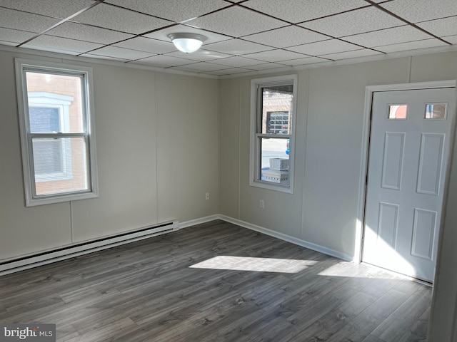 empty room featuring a baseboard radiator, dark wood-type flooring, and a paneled ceiling