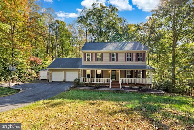 colonial home featuring covered porch, a front yard, and a garage