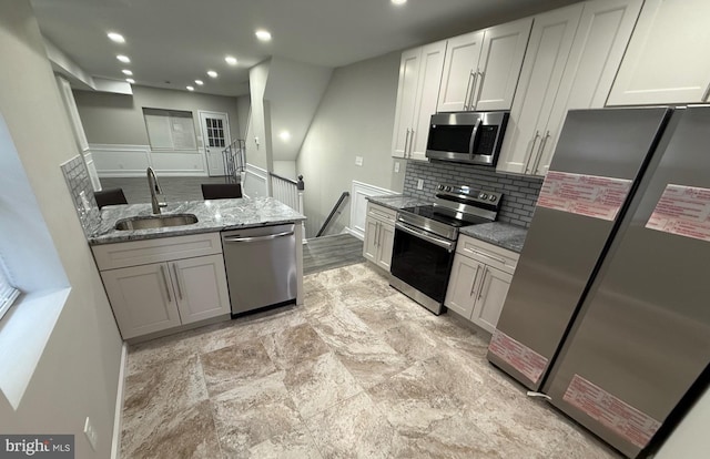 kitchen featuring white cabinets, sink, tasteful backsplash, light stone countertops, and appliances with stainless steel finishes