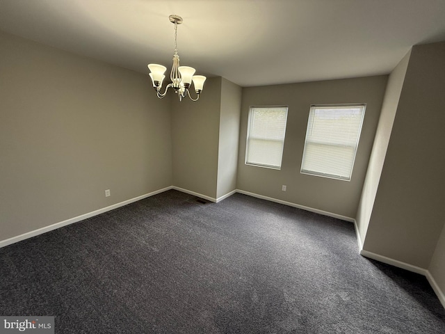 carpeted empty room with an inviting chandelier