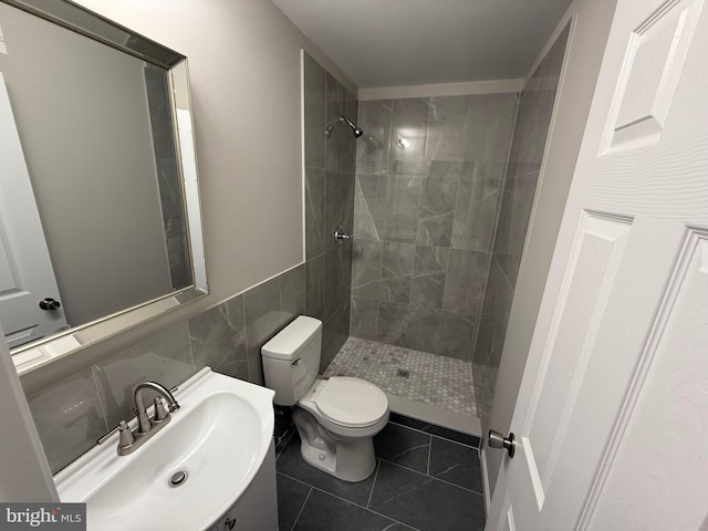 bathroom with toilet, tile walls, tile patterned floors, and a tile shower