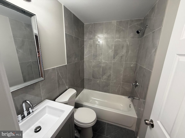 full bathroom with tile walls, vanity, tiled shower / bath, tile patterned floors, and toilet