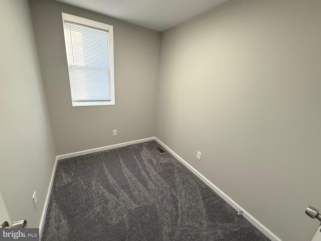 spare room with dark carpet