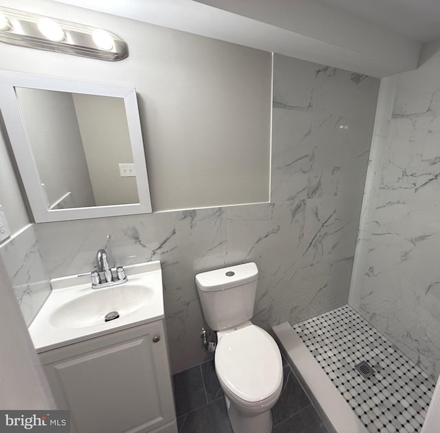 bathroom featuring tiled shower, vanity, toilet, and tile walls