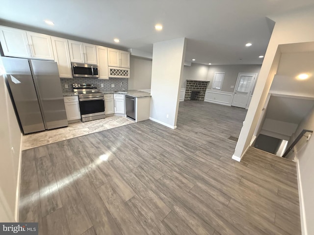 kitchen featuring sink, white cabinetry, tasteful backsplash, hardwood / wood-style flooring, and stainless steel appliances