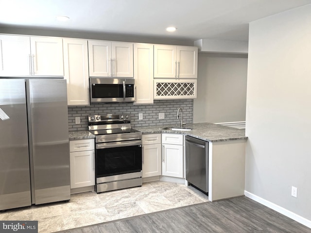 kitchen with sink, appliances with stainless steel finishes, backsplash, light stone countertops, and white cabinets