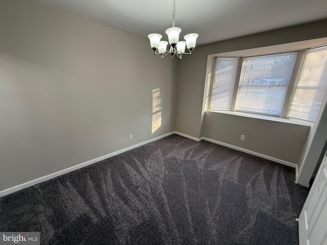 carpeted empty room featuring a chandelier