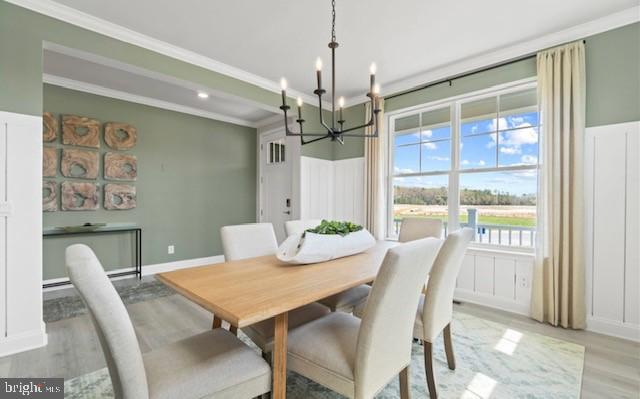 dining room with light hardwood / wood-style floors, a notable chandelier, and crown molding