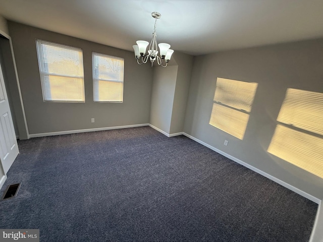 carpeted spare room with a notable chandelier