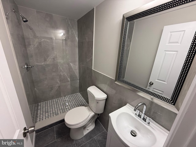 bathroom with a tile shower, tile patterned floors, vanity, and toilet