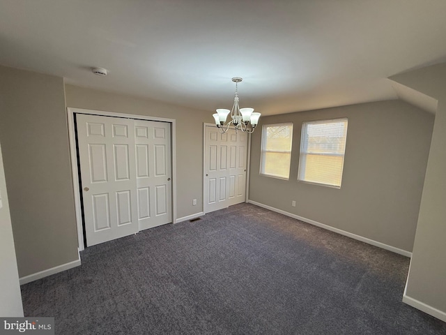 unfurnished bedroom with dark carpet, vaulted ceiling, and a notable chandelier