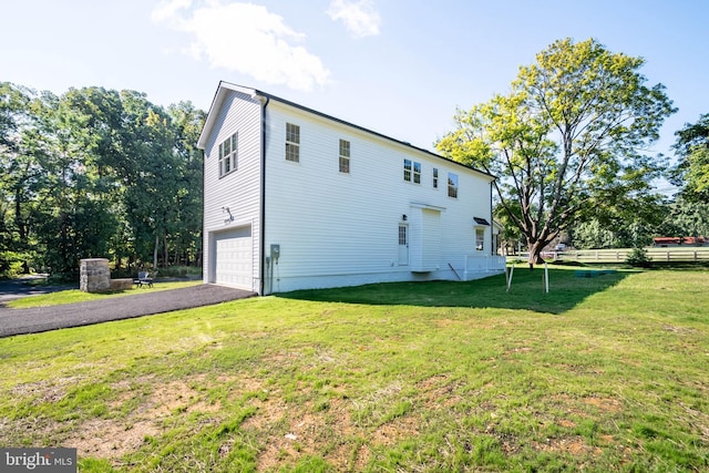 back of house with a garage and a lawn