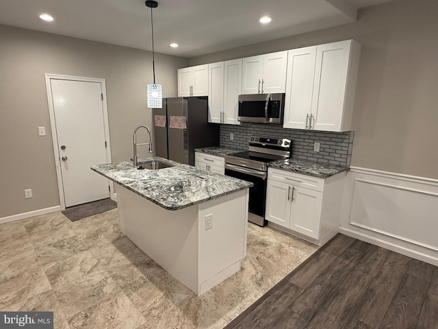 kitchen with a center island with sink, light stone countertops, sink, and appliances with stainless steel finishes