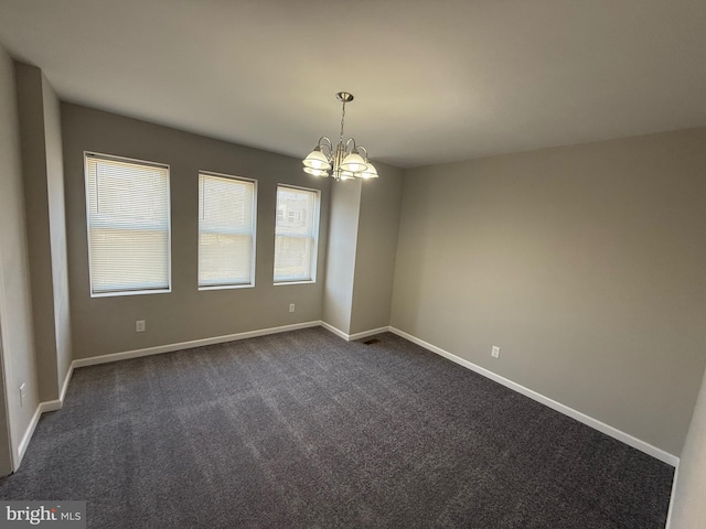 spare room with a chandelier and dark colored carpet