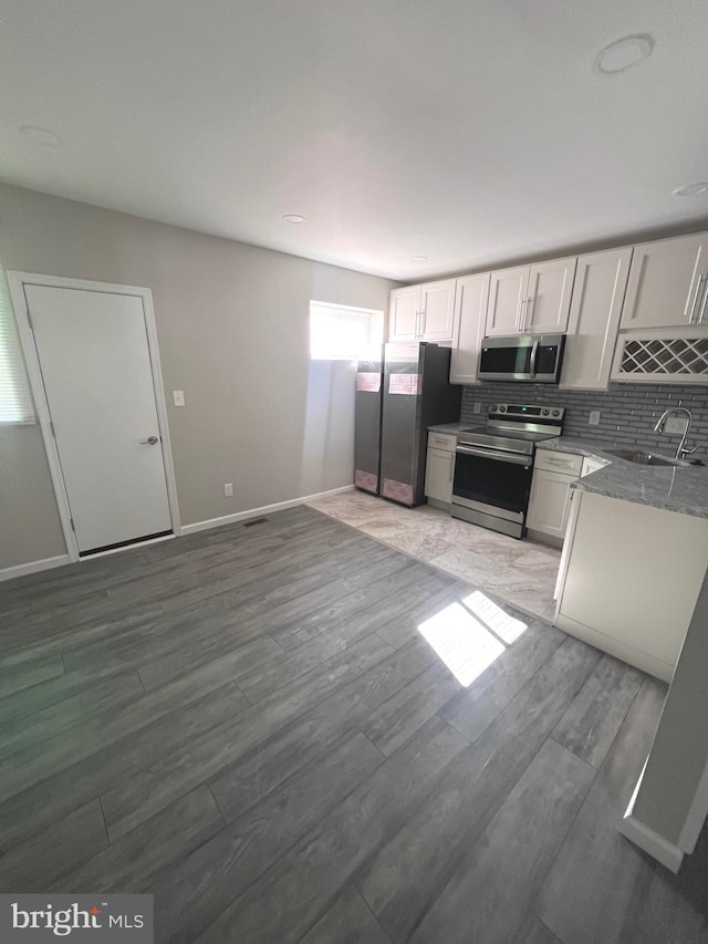 kitchen featuring sink, backsplash, stainless steel appliances, and white cabinets