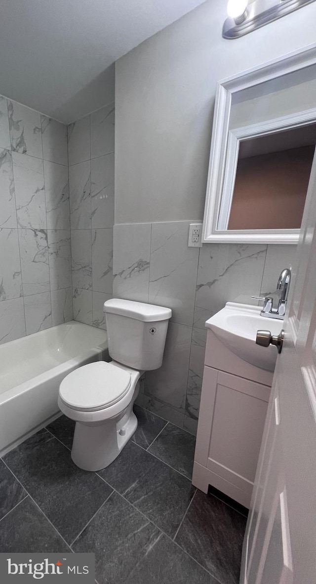 bathroom featuring vanity, tile walls, and toilet