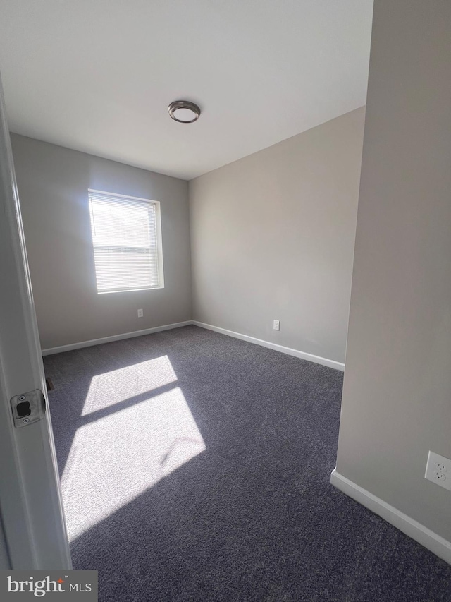 unfurnished room with dark carpet