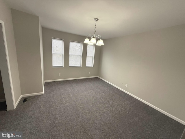 carpeted empty room with an inviting chandelier