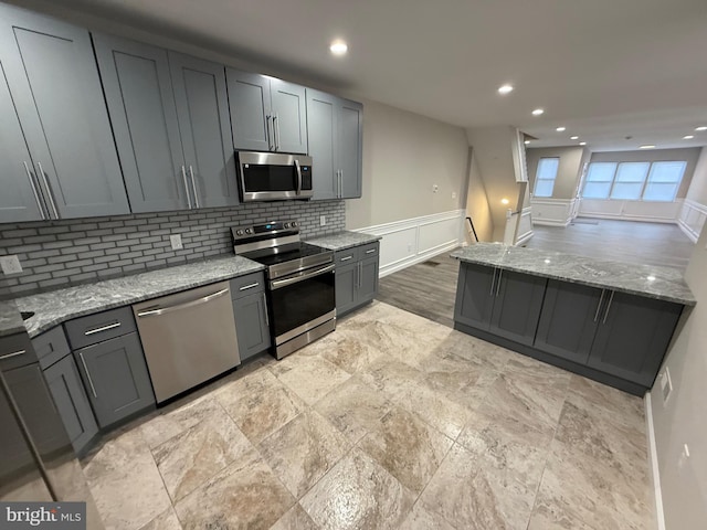 kitchen featuring gray cabinets, light stone countertops, and appliances with stainless steel finishes