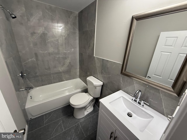 full bathroom featuring vanity, tiled shower / bath combo, tile walls, tile patterned flooring, and toilet