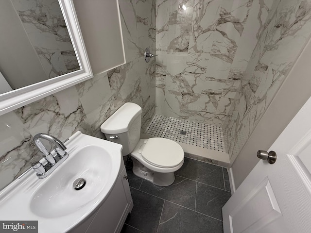 bathroom with a shower, vanity, tile walls, and toilet