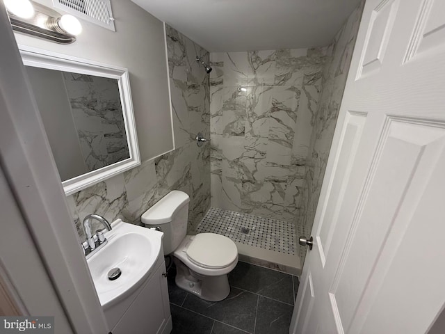 bathroom with vanity, toilet, a tile shower, and tile walls