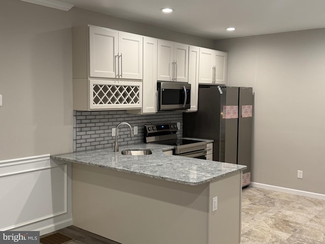 kitchen featuring white cabinetry, sink, stainless steel appliances, light stone counters, and kitchen peninsula