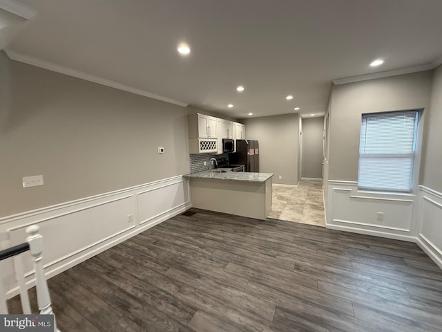 kitchen featuring white cabinets, black appliances, crown molding, light stone counters, and kitchen peninsula