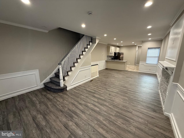 unfurnished living room featuring ornamental molding and dark wood-type flooring