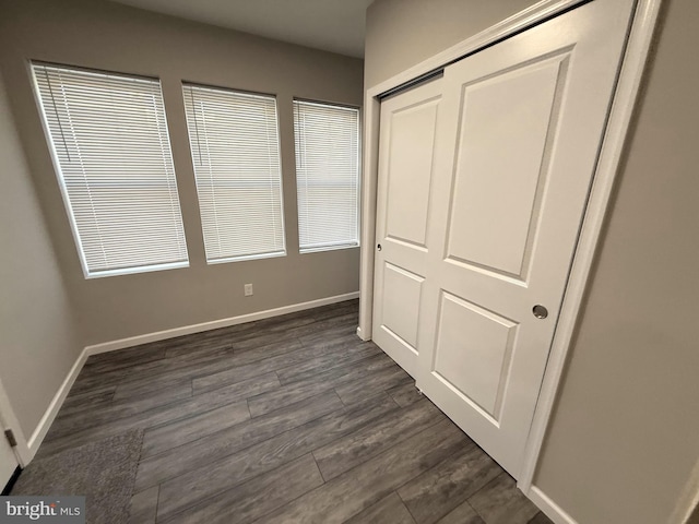 unfurnished bedroom with dark hardwood / wood-style flooring and a closet