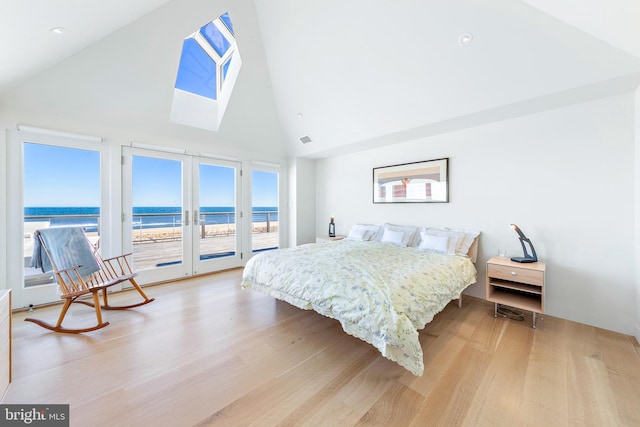bedroom with high vaulted ceiling, access to exterior, a water view, and light wood-style flooring