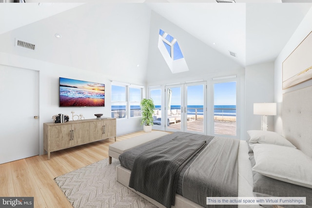 bedroom with visible vents, light wood-style floors, access to exterior, high vaulted ceiling, and a skylight