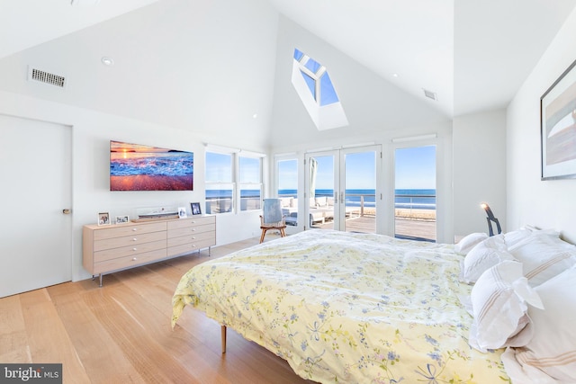 bedroom featuring a skylight, access to exterior, multiple windows, visible vents, and high vaulted ceiling