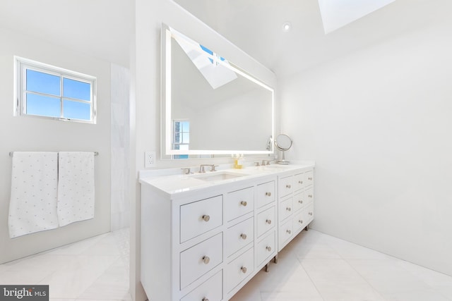 full bathroom featuring double vanity, a skylight, plenty of natural light, and a sink