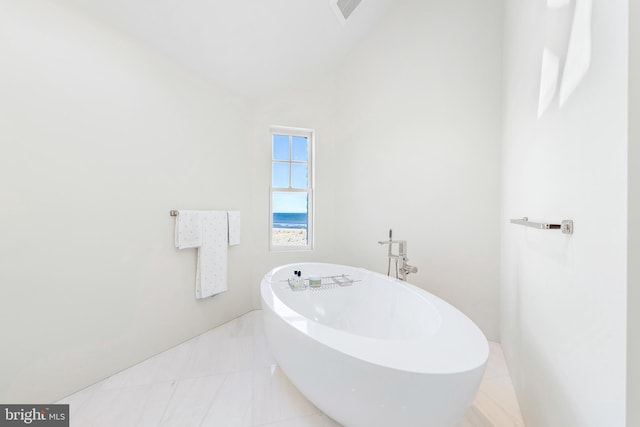 full bath featuring lofted ceiling, visible vents, a soaking tub, and tile patterned floors