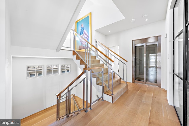 stairs with a wealth of natural light and hardwood / wood-style flooring