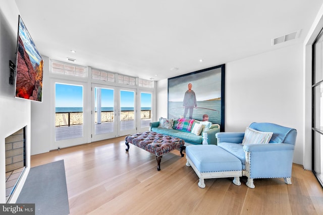 living room featuring visible vents, wood finished floors, and a fireplace with flush hearth
