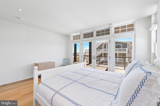 bedroom featuring access to exterior, french doors, light hardwood / wood-style floors, and multiple windows