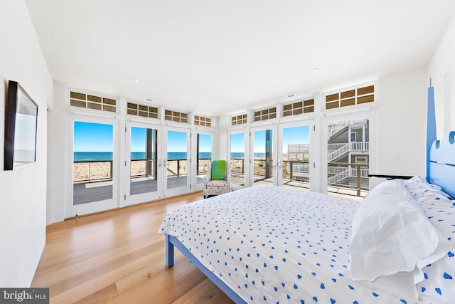 bedroom with wood finished floors, a water view, and access to outside