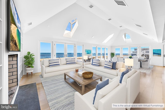 living area featuring visible vents, high vaulted ceiling, a skylight, and wood finished floors